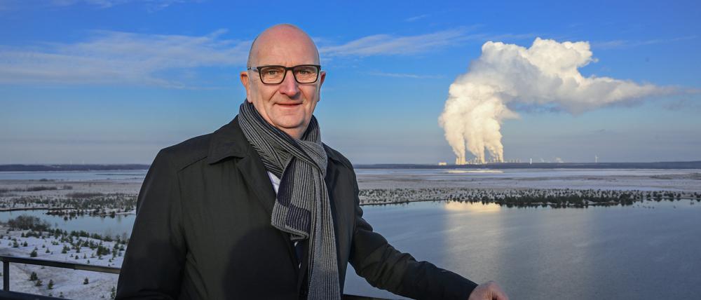 30.11.2023, Brandenburg, Cottbus: Dietmar Woidke (SPD), Ministerpräsident von Brandenburg, steht im Rahmen einer Pressefahrt auf dem Aussichtsturm am Rand der Cottbusser Ostsee vor der Kulisse des Kaftwerkes Jänschwalde. Foto: Soeren Stache/dpa +++ dpa-Bildfunk +++