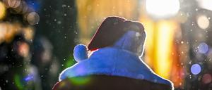 Ein Weihnachtsmann geht niedergeschlagen auf dem Weihnachtsmarkt vor dem Roten Rathaus bei leichtem Schneefall. 