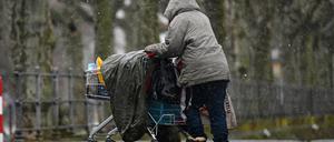 Eine obdachlose Frau schiebt ihr Hab und Gut in einem Einkaufswagen.