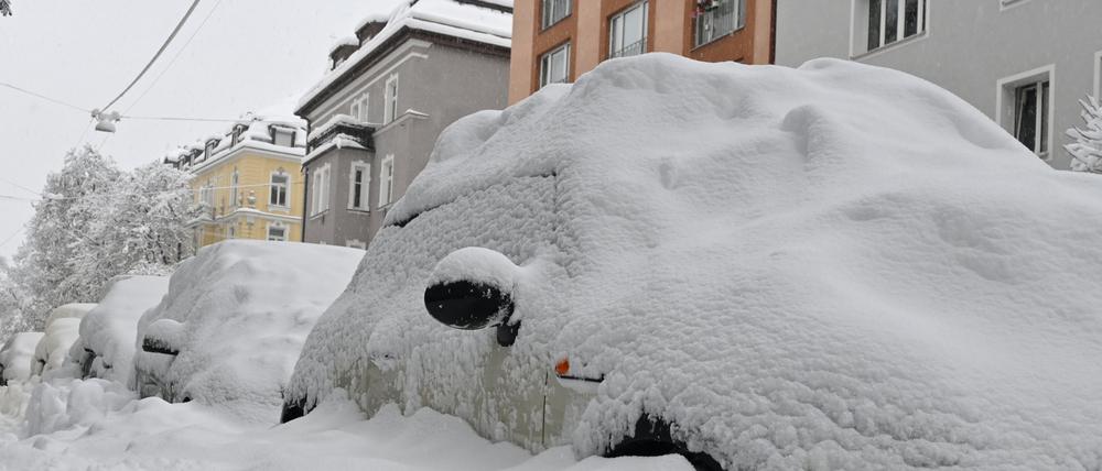 Eine dicke Schneeschicht liegt auf parkenden Autos in München.