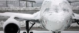 Ein verschneites Flugzeug steht am Flughafen in München.