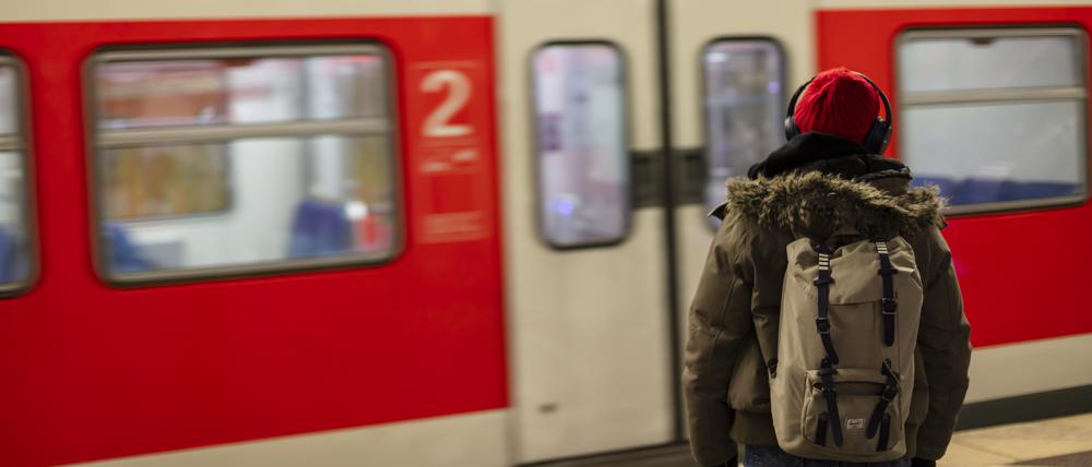 A man with a red cap and headphones waiting for the S-Bahn train at the Munich main train station.
