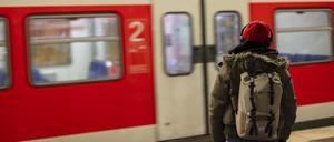 A man with a red cap and headphones waiting for the S-Bahn train at the Munich main train station.