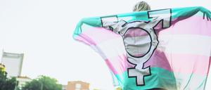 Person mit Flagge, die nicht-binäre Menschen symbolisiert. 