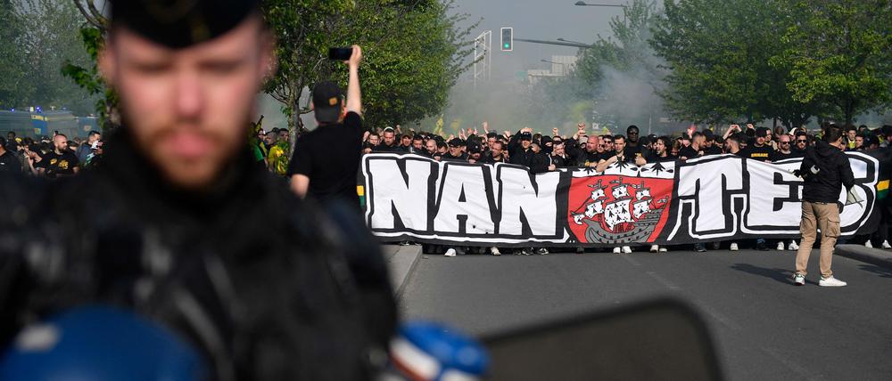 Auf Krawall gebürstet. Ein französischer Gendarm steht vor den Fans vom FC Nantes, die vor dem Spiel ein Transparent hochhalten.