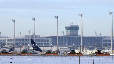Flughafenmitarbeiter räumen Schnee und Eis vom Vorfeld zwischen den Flugzeugen. 