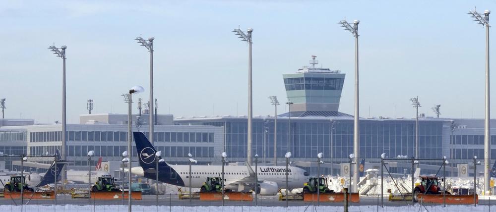 Flughafenmitarbeiter räumen Schnee und Eis vom Vorfeld zwischen den Flugzeugen.