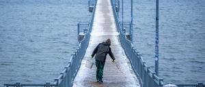 Auf der Seebrücke von Wismar wird die Schneedecke mit Sand abgestreut.