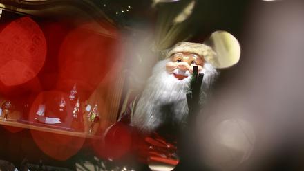 05.12.2023, Sachsen-Anhalt, Derenburg: Blick durch einen beleuchteten Weihnachtsbaum auf einen Weihnachtsmann in der Weihnachtsausstellung der Glasmanufaktur Harzkristall in Derenburg. 