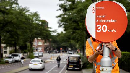 Ein Angestellter der Stadtverwaltung montiert ein Tempo-30-Schild an einer Straße in Amsterdam.