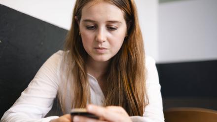 Eine junge Frau schaut auf ihr Smartphone. 