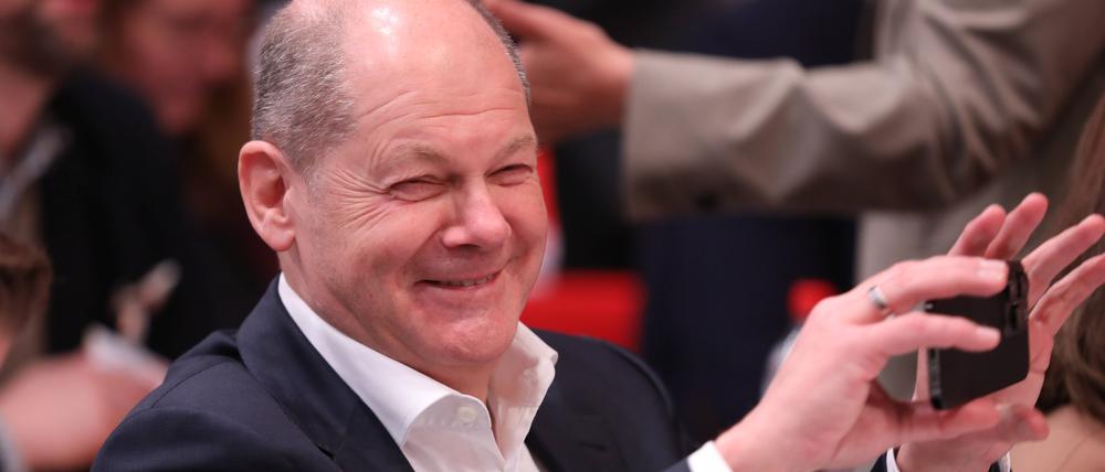 Bundeskanzler Olaf Scholz fröhlich und mit Smartphone in der Hand auf dem SPD-Bundesparteitag.