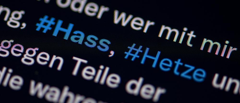 Auf dem Bildschirm eines Smartphones sieht man die Hashtags (#) Hass und Hetze in einem Twitter-Post.