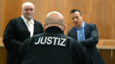 Ein Justizbeamter steht vor der Urteilsverkündung im Gerichtssaal im Landgericht Hannover vor den Anwälten der Angeklagten. 