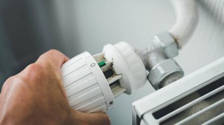  29 July 2022: male hand turns heating thermostat to zero to save electricity, gas and heating costs, hand regulates radiator *** männliche Hand dreht das Thermostat der Heizung auf Null um Strom, Gas und Heizkosten zu Sparen, Hand reguliert Heizkörper