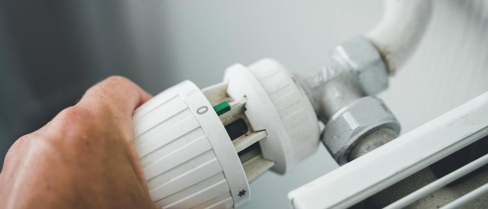  29 July 2022: male hand turns heating thermostat to zero to save electricity, gas and heating costs, hand regulates radiator *** männliche Hand dreht das Thermostat der Heizung auf Null um Strom, Gas und Heizkosten zu Sparen, Hand reguliert Heizkörper