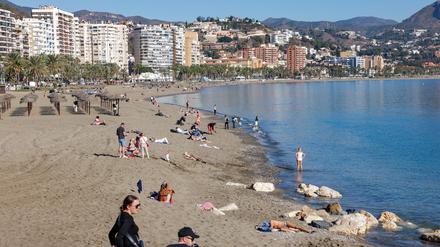 Menschen genießen das warme Wetter am Strand von Malaga.