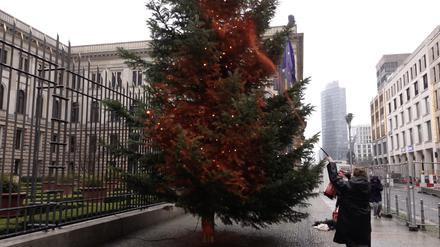 Ein Mitglied der Klimaschutzgruppe „Letzte Generation“ besprüht einen Weihnachtsbaum vor dem Bundesrat mit orangener Farbe.