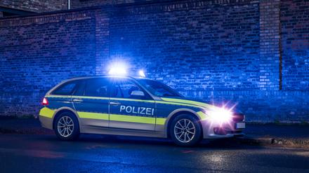 Ein Polizeiauto mit eingeschaltetem Blaulicht bei Nacht. (Symbolbild)