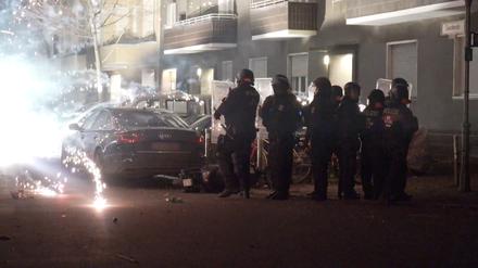 Polizisten stehen in der Silvesternacht 2022 hinter explodierendem Feuerwerk.