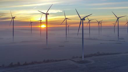 Hinter Wolkenschleiern geht in Brandenburg die Sonne über dem Windenergiepark Odervorland auf.