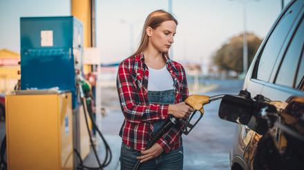 Eine Frau betankt an einer Tankstelle sein Auto. 
