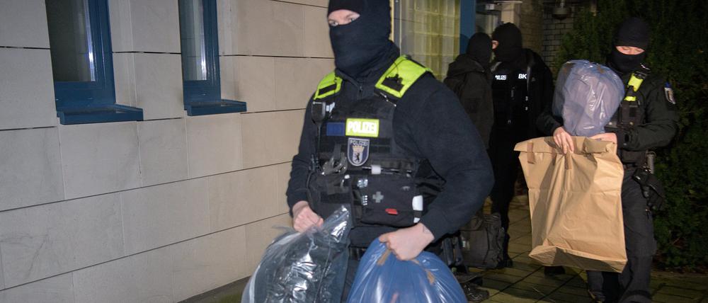 Durchsuchungen in Berlin: Polizisten tragen sichergestellte Beweismittel aus einem Haus.