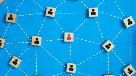 Leadership and network teamwork concepts Red businessman icon on the wooden block in the middle between the black business icon on the wooden blocks. Depicts network and work that is a perfect team.