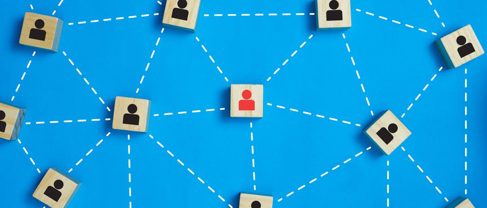 Leadership and network teamwork concepts Red businessman icon on the wooden block in the middle between the black business icon on the wooden blocks. Depicts network and work that is a perfect team.