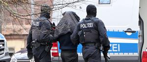Eine Person wird von Polizisten bei einem Hubschrauberlandeplatz von einem Hubschrauber zu einem Auto geführt. Die Bundesanwaltschaft hatte am 14.12.2023 in Berlin und im niederländischen Rotterdam vier mutmaßliche Mitglieder der islamistischen Hamas festnehmen lassen. 