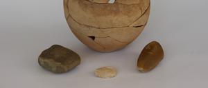 Der Krug aus der jordanischen Wüste enthielt ein Bruchstück eines Mahlsteins („Läufer“, links) eine Muschelschale aus dem Euphrat (Mitte) und einen bearbeiteten Kieselstein (rechts). 