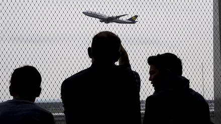 Eine Familie sieht sehnsüchtig einem Flugzeug hinterher. (Symbolbild)