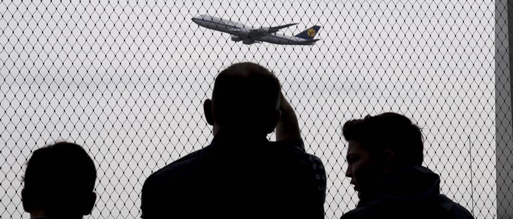 Eine Familie sieht sehnsüchtig einem Flugzeug hinterher. (Symbolbild)