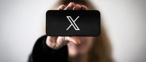 A woman holds a smartphone displaying the logo of US social network X (former Twitter), in Nantes, western France, on November 29, 2023. (Photo by LOIC VENANCE / AFP)