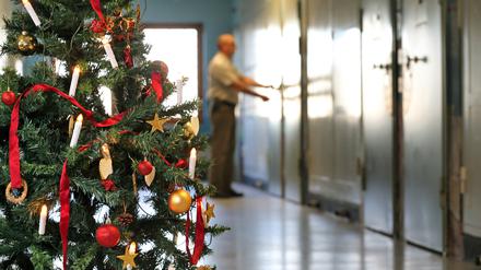 Auf einem mit einem Weihnachtsbaum geschmückten Gefängnisflur schließt ein Justizvollzugsbeamter eine Zellentür ab. 