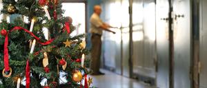 Auf einem mit einem Weihnachtsbaum geschmückten Gefängnisflur schließt ein Justizvollzugsbeamter eine Zellentür ab. 