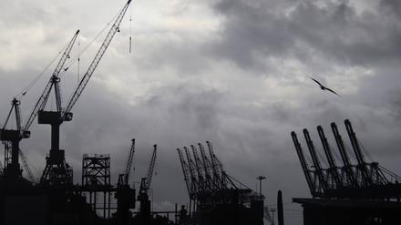 Containerbrücken und Werftkräne im Hamburger Hafen vor einem dunkelgrauen Himmel. 