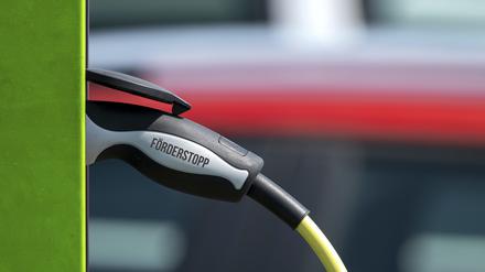 Ein symbolischer E-Auto-Ladestecker mit der Aufschrift „Förderstopp“ steckt in einer Ladesäule. 