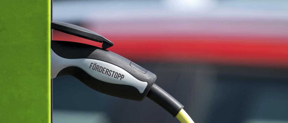 Ein symbolischer E-Auto-Ladestecker mit der Aufschrift „Förderstopp“ steckt in einer Ladesäule.