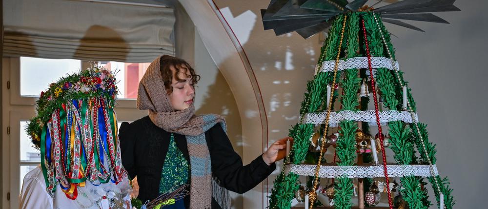 Das Jänschwalder Christkind (l.), aus sorbisch  Janöojski bog, und eine Begleiterin stehen an einem sogenannten Drehboom (Drehbaum), ein historischer Weihnachtsschmuck aus dem Spreewald.