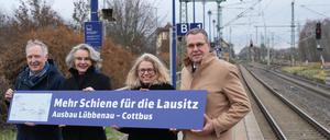 19.12.2023, Brandenburg, Lübbenau: Alexander Kaczmarek (l-r), Konzernbevollmächtigter der Deutschen Bahn für Brandenburg, Susanne Henckel, Staatssekretärin im Bundesverkehrsministerium, Ute Bonde, Geschäftsführerin des VBB, und Rainer Genilke (CDU), Brandenburger Minister für Infrastruktur und Landesplanung, stehen während eines Pressetermins zum Ausbau der Bahnverbindung zwischen Lübbenau und Cottbus auf dem Bahnsteig des Bahnhofs Lübbenau und halten ein Schild mit der Aufschrift ·Mehr Schiene für die Lausitz - Ausbau Lübbenau - Cottbus·. Foto: Soeren Stache/dpa - Honorarfrei nur für Bezieher des Dienstes ZB-Funkregio Ost +++ ZB-FUNKREGIO OST +++