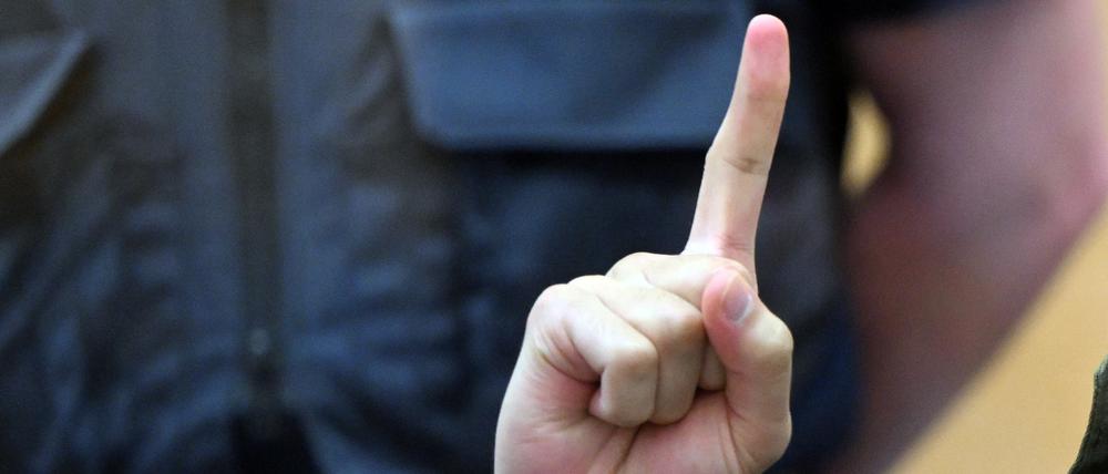 Der Angeklagte Maan D. wartet im Prozess um die Messerattacken von Duisburg auf den Beginn der Verhandlung und zeigt den Gruß der Kämpfer des IS, Tauhid.