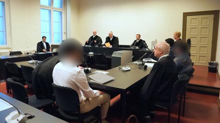Die angeklagten syrischen Brüder (3.v.l und r) sitzen zu Beginn des Prozesses wegen mutmaßlicher Vorbereitung eines Sprengstoffanschlags neben ihren Anwälten im Sitzungssaal im Strafjustizgebäude. (Archivbild). 