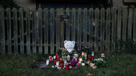 Kerzen, Blumen und ein großer Plüschteddy sind vor einem Zaun am Fundort zu sehen, wo die Leiche einer vermissten 14-Jährigen aus Nordhessen in einem Waldstück gefunden wurde. 