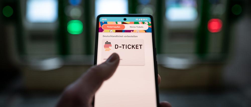 Ein Mann hält ein Mobiltelefon, auf dem das ·D-Ticket· gekauft werden kann, vor Ticketautomaten am Hauptbahnhof in der Hand (Archivbild).