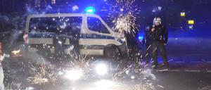 Polizeibeamte stehen am Silvesterabend hinter explodierendem Feuerwerk. 