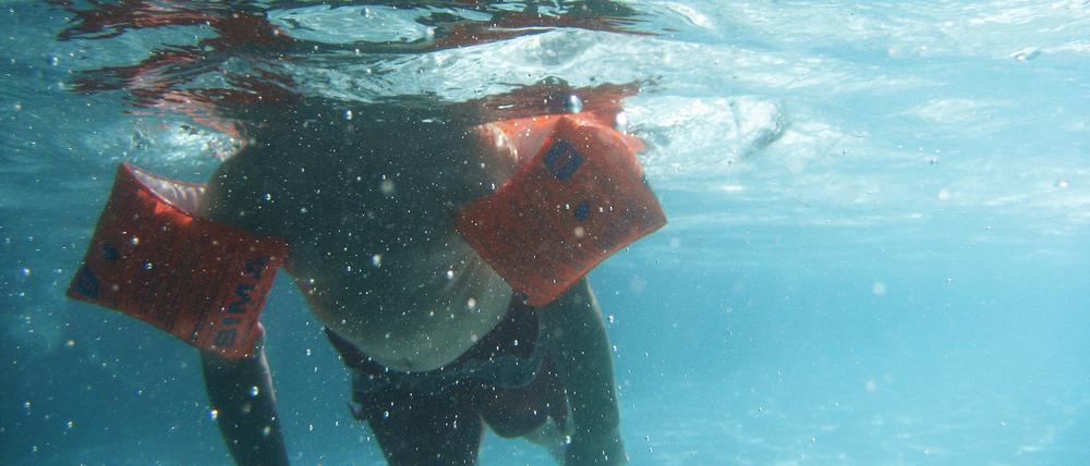 Ein Kind schwimmt unter Wasser.