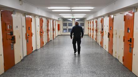 Ein Vollzugsbeamter geht in der Zugangsabteilung der Justizvollzugsanstalt Moabit an Zellentüren vorbei.