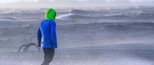 Ein Spaziergänger läuft am 22.12.2023 bei Sturmflut und Wellen am Ufer der Wesermündung in Bremerhaven entlang.