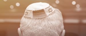 Ein Mann trägt eine Kippa mit eingearbeiteten israelischen und deutschen Fahnen. 